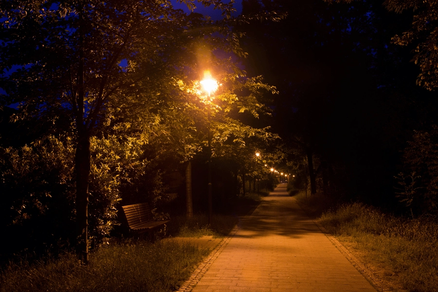 dark walking path lit up by street lamps at night